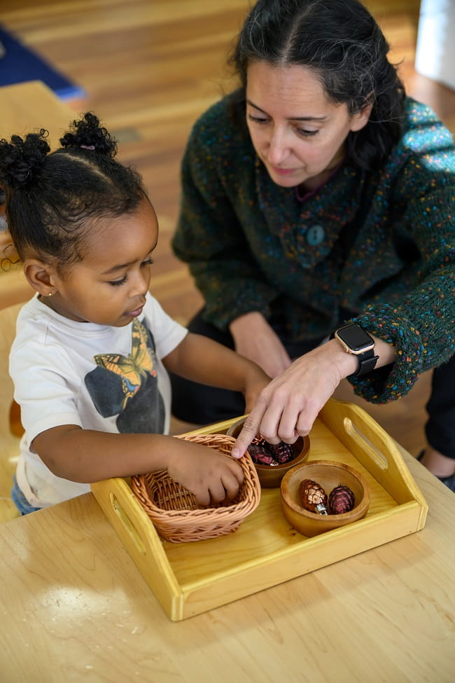 Teacher with Black Child on Floor of Montessori Classroom